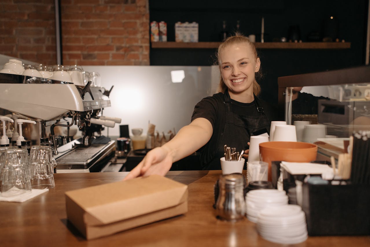 Coffee shop worker smiling and holding a box